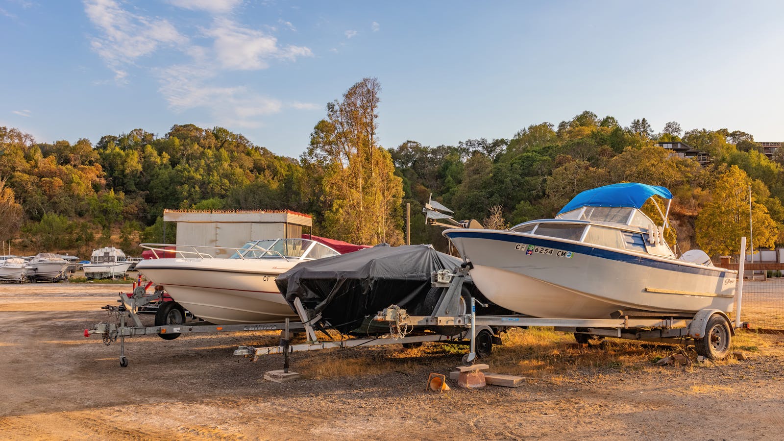 Motorboats on trailers set against a lush, green landscape under a clear sky.